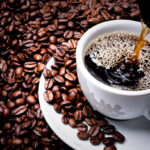 Café preto na xícara com grãos de café em volta