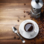 grãos de café proximo à xícara de café