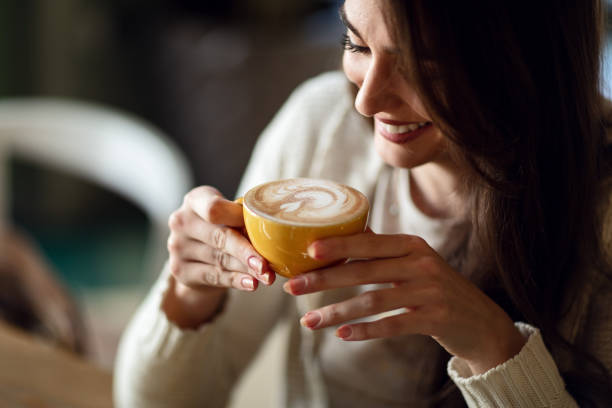 Mulher sorridente jovem segurando uma xícara de café com leite.