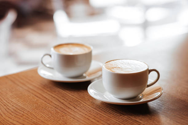 Duas xícaras de cappuccino com latte art na mesa de madeira em casa