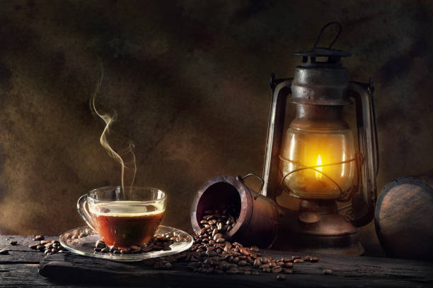 Vidro de xícara de café e lanterna de óleo de lâmpada de querosene vintage queimando com piso de madeira envelhecido com luz suave e brilhante.