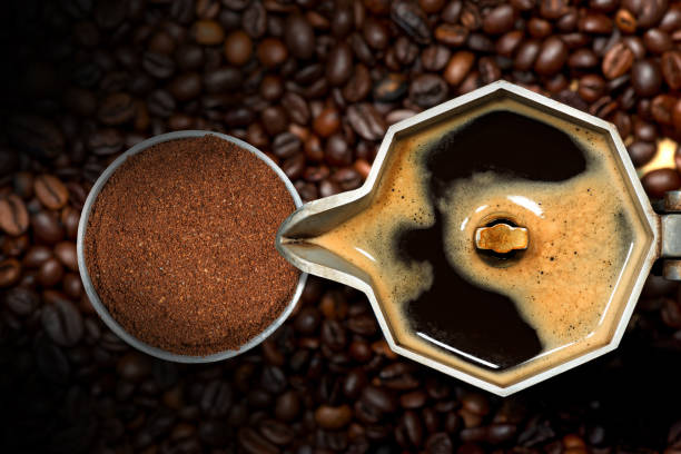 Close-up de uma cafeteira italiana aberta com café moído em um filtro de metal, em muitos grãos de café torrados, vista superior